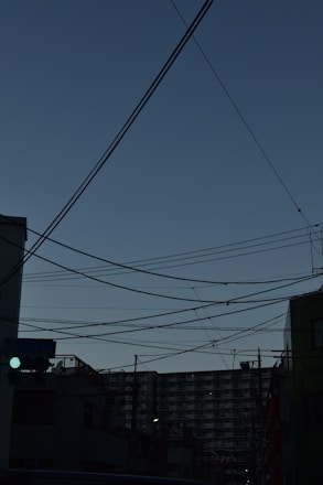 Modern energy grid with blue and green electric lines glowing over a cityscape at dusk.