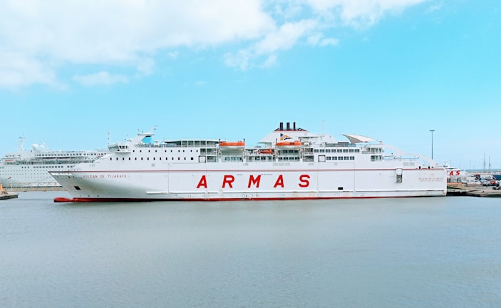 white and red ship on sea under blue sky during daytime