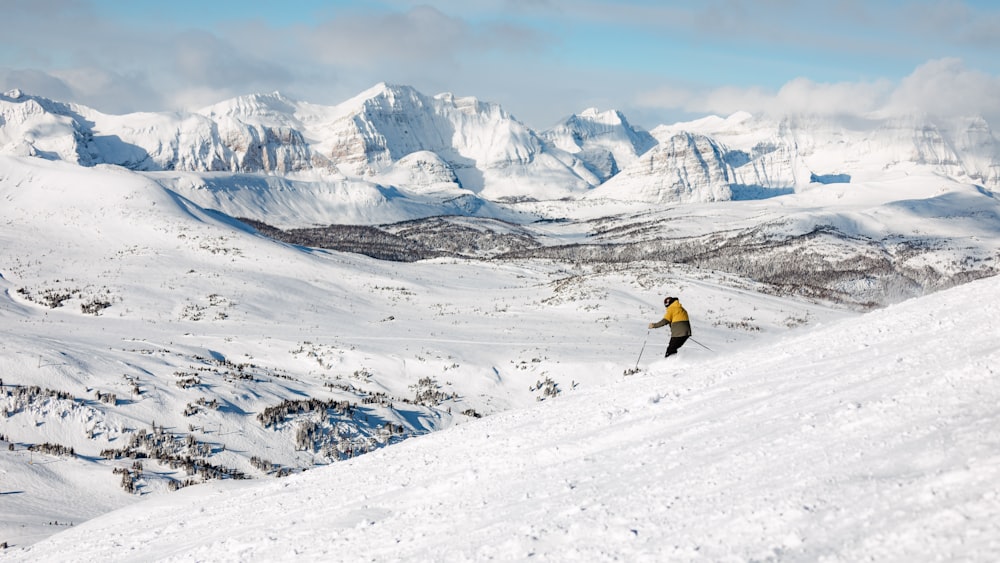 person in black jacket and blue denim jeans standing on snow covered mountain during daytime