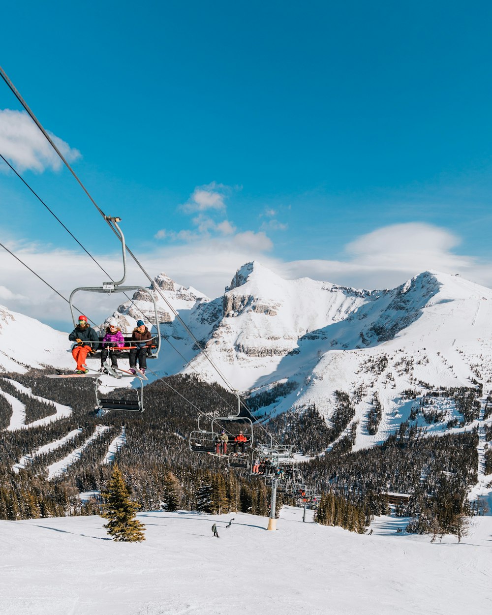 people riding ski lift over snow covered mountain during daytime