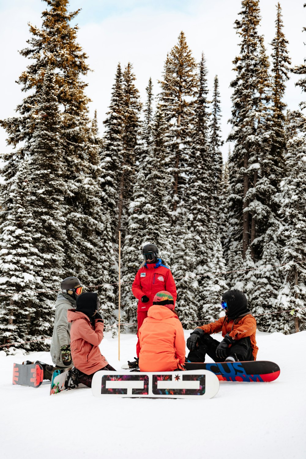 people in red jacket sitting on snow covered ground during daytime