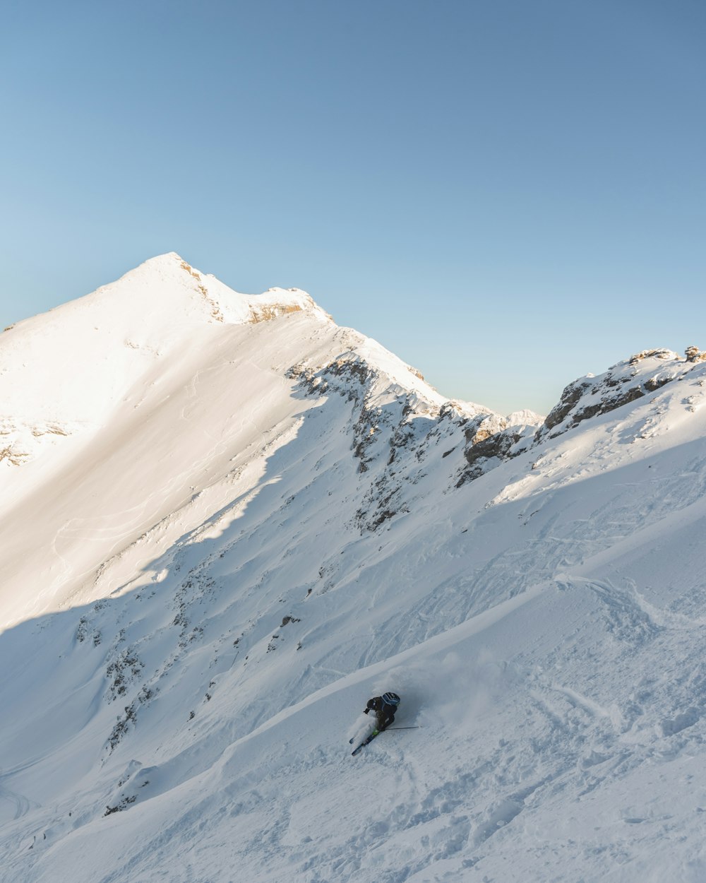 person in black jacket standing on snow covered mountain during daytime