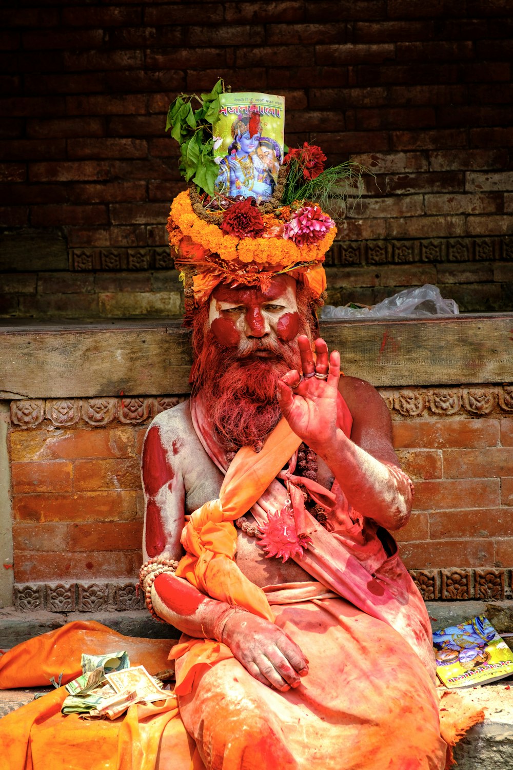 man in red and yellow traditional dress sitting on brown concrete stairs