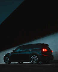 An atmospheric image of a terracotta-colored car parked against a charcoal urban backdrop at dusk.