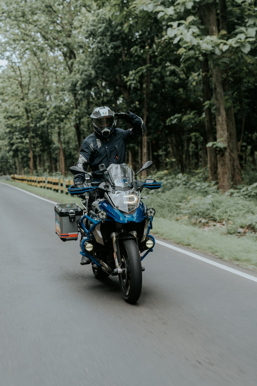 hombre con chaqueta negra montando motocicleta en la carretera durante el día