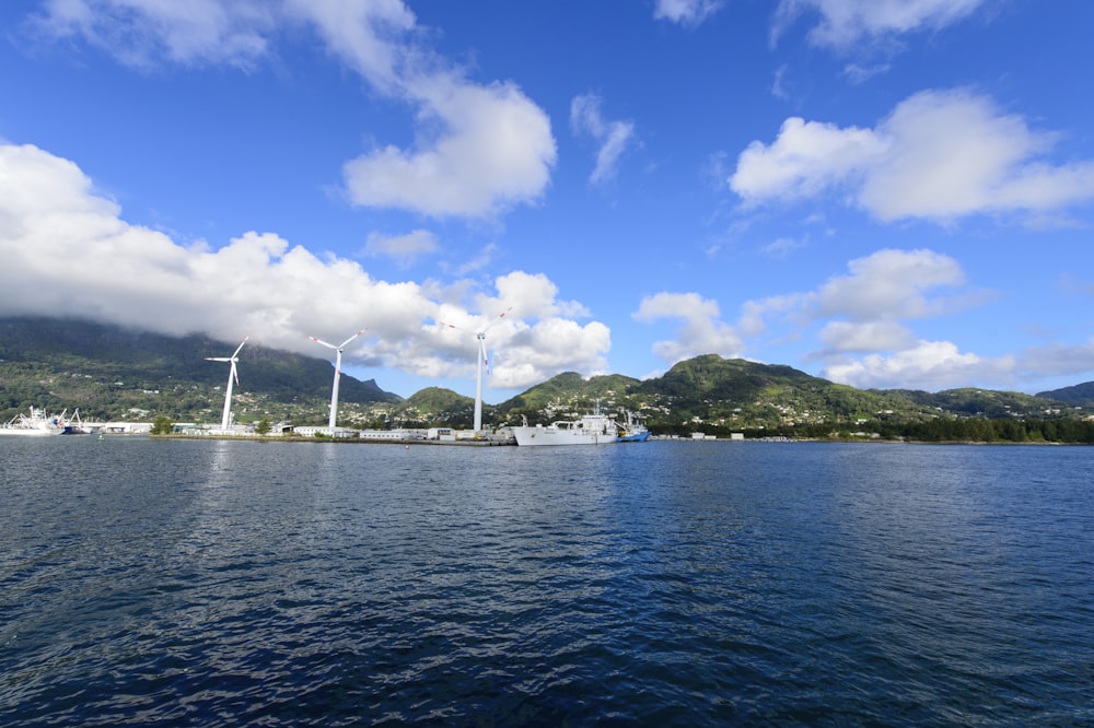 white boat on sea near green mountain under blue sky during daytime