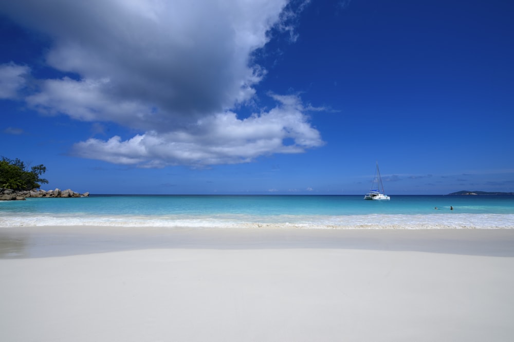 white sailboat on sea under blue sky and white clouds during daytime