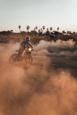 man riding motorcycle on brown field during daytime