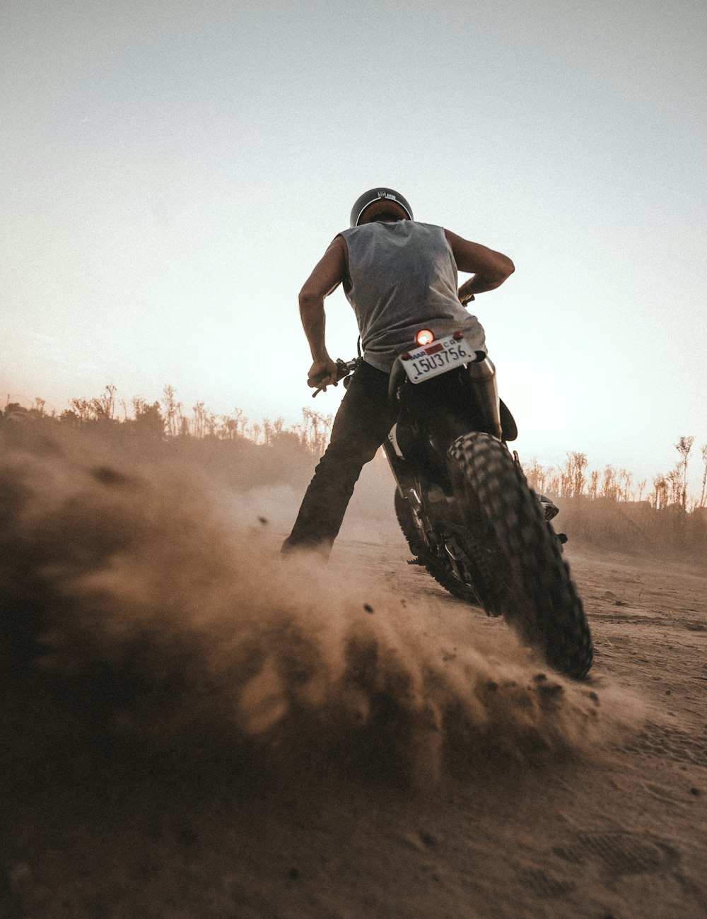 Mann in schwarzem T-Shirt und schwarzer Hose fährt Motocross-Dirtbike auf braunem Feld während