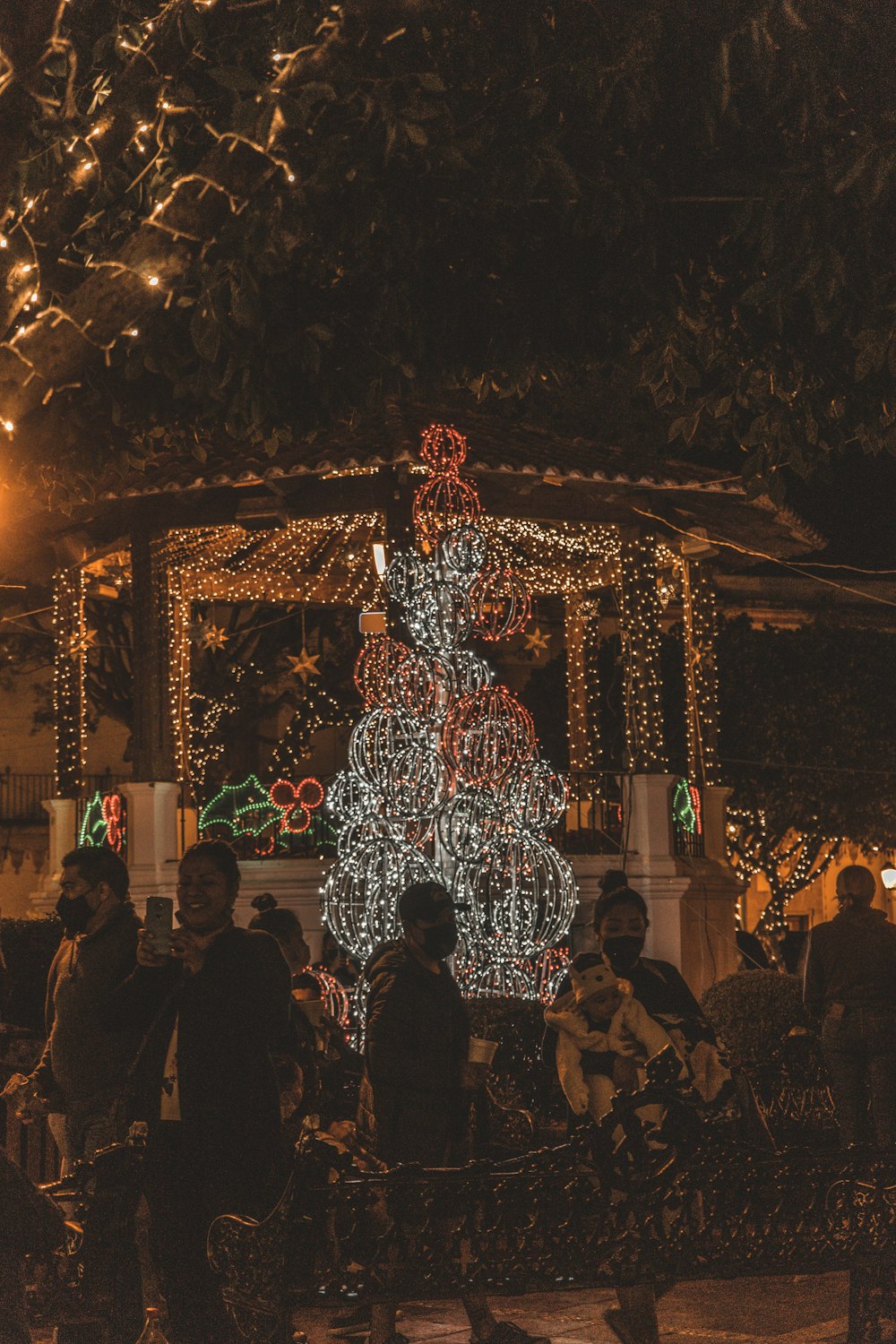 people standing near white and blue floral arch during night time