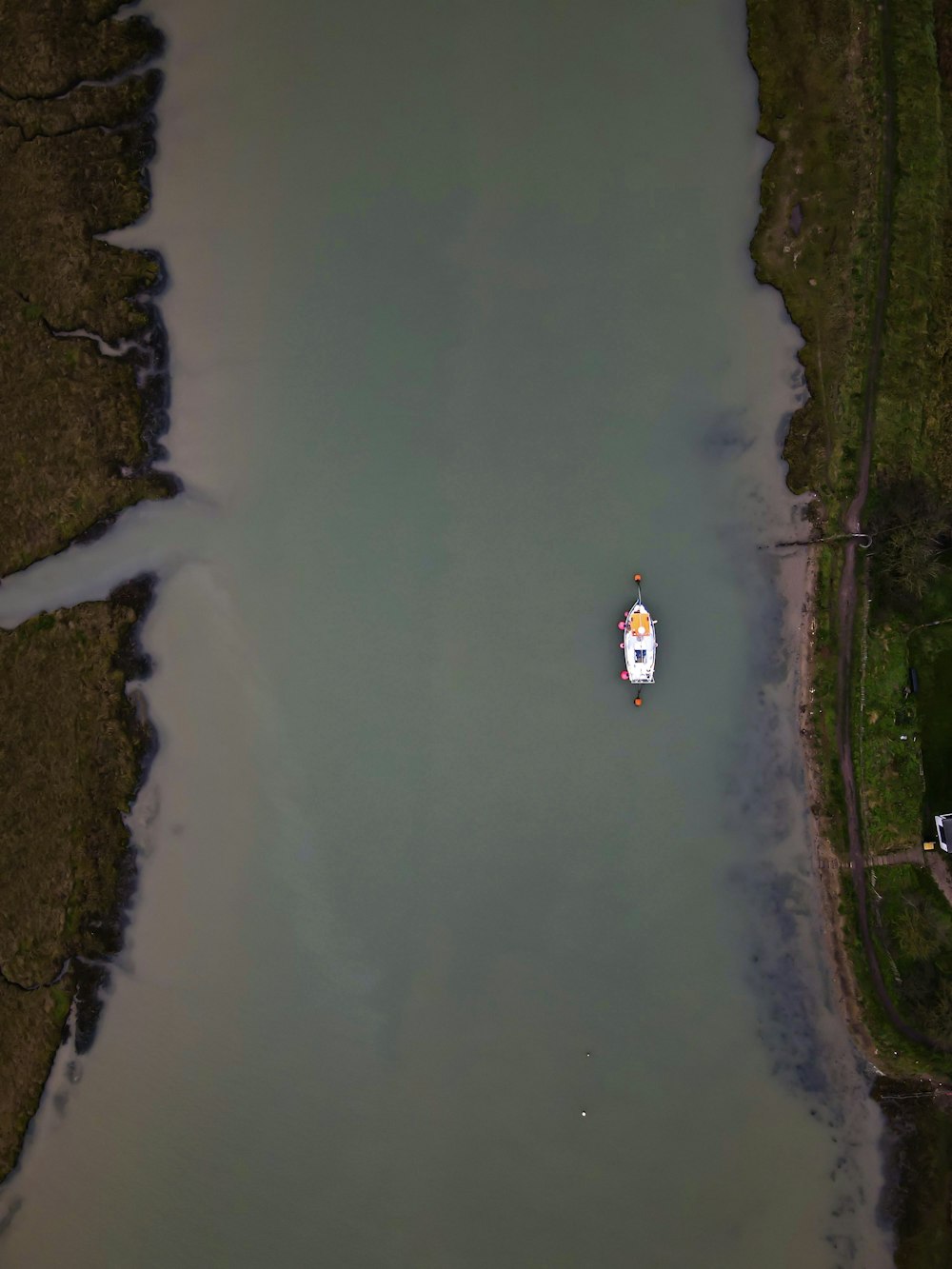 person in white shirt and black pants standing on brown soil near body of water during