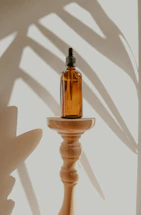 Elegant glass spray bottle resting on a polished wooden surface with a blurred high-end lake home in the background.