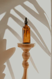 A sleek amber room spray bottle resting on a linen cloth next to a sprig of lavender.