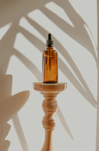 A sleek amber room spray bottle resting on a linen cloth next to a sprig of lavender.