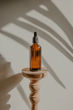 Sunlight filtering through leaves onto botanical serums in glass dropper bottles.