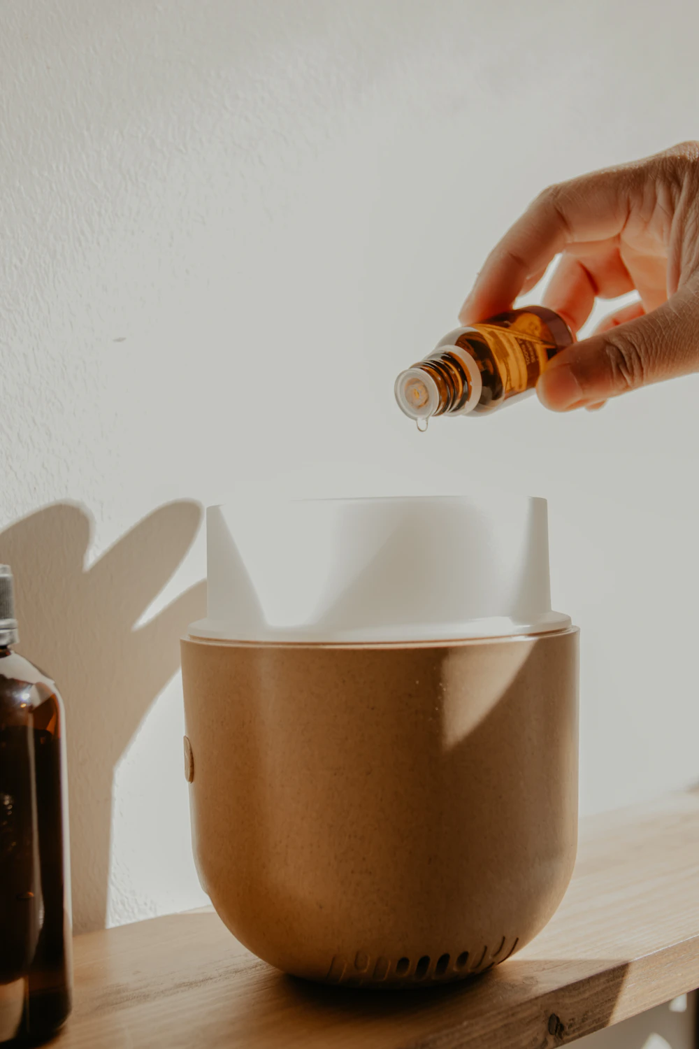 Hand pouring essential oil into a ceramic diffuser