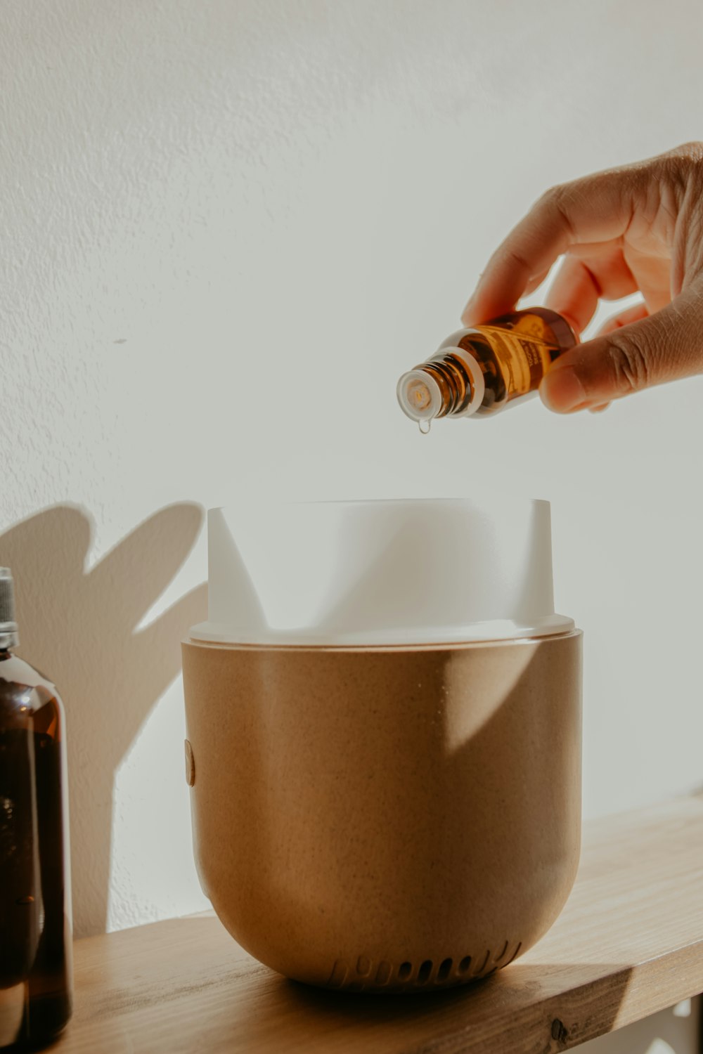 person holding essential oil dropping into diffuser