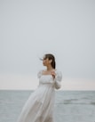 woman in white long sleeve dress standing on seashore during daytime