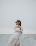 woman in white long sleeve dress standing on seashore during daytime