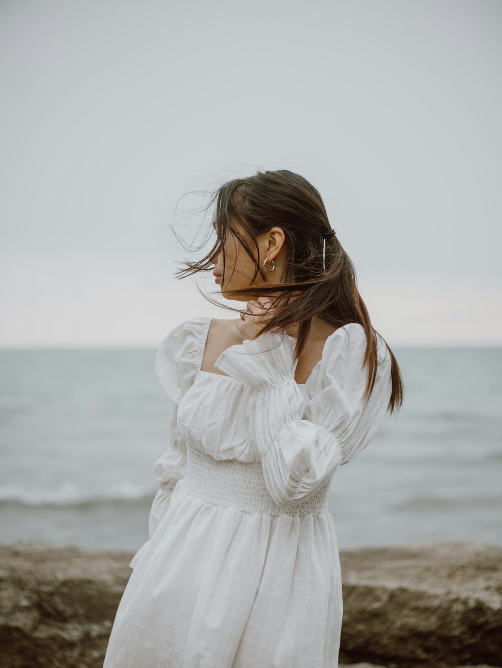 woman in white long sleeve dress standing on beach during daytime