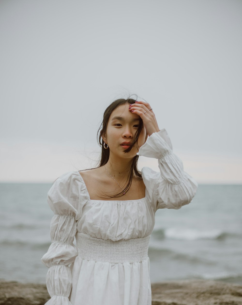 woman in white long sleeve shirt standing near body of water during daytime