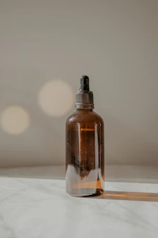 Close-up of golden Jager energy oil in a glass dropper bottle resting on a smooth wooden surface with soft natural light.