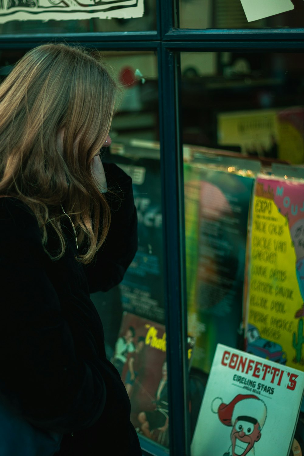 woman in black jacket standing beside glass window