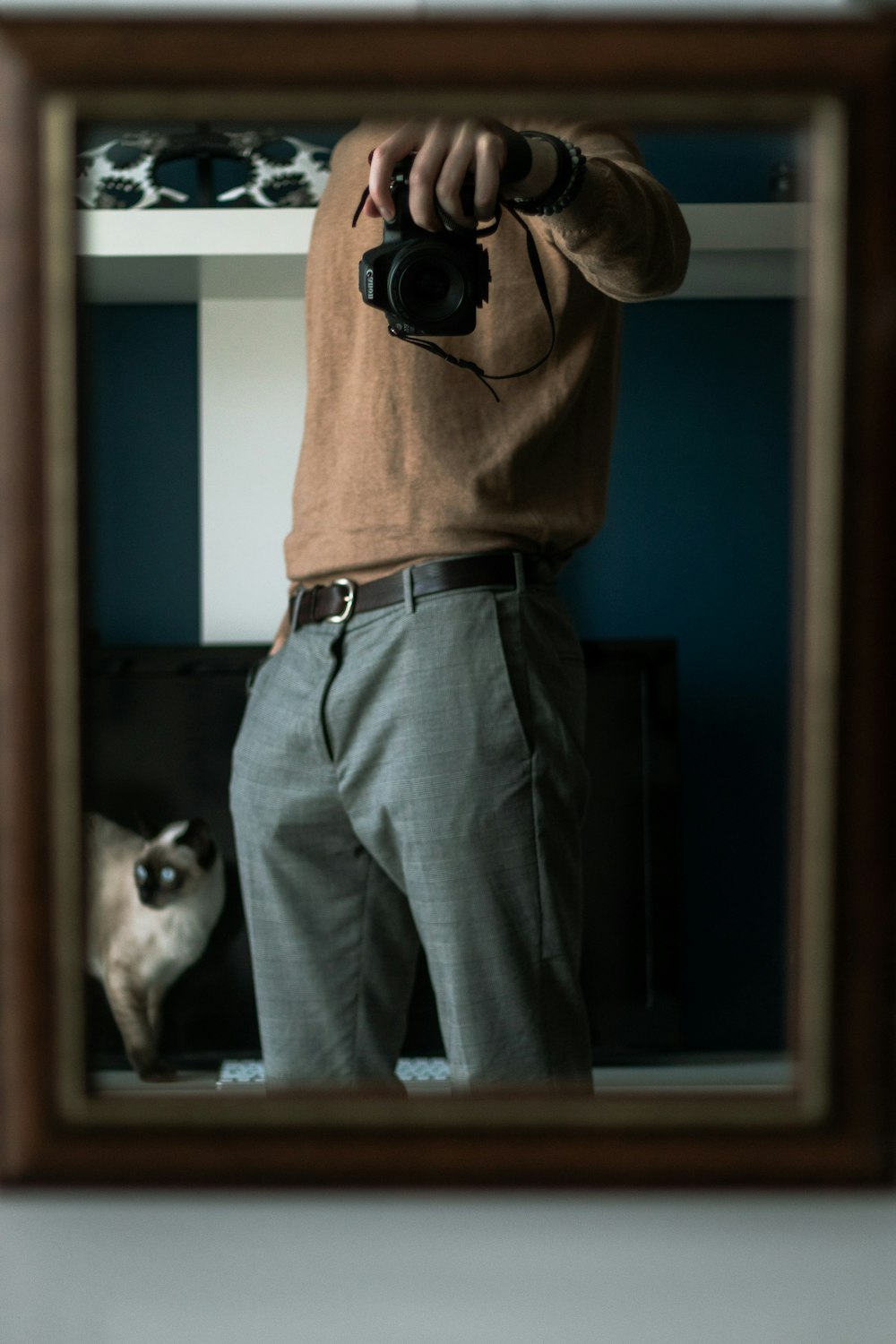 man in brown long sleeve shirt and gray denim jeans holding black camera