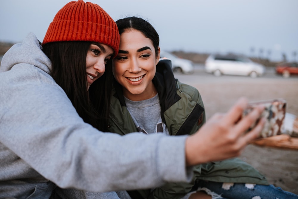 man in gray jacket hugging woman in red knit cap