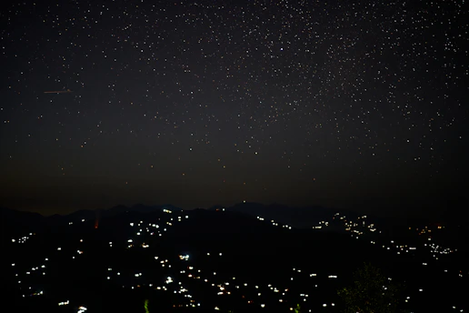 A serene night sky over a quiet village, stars twinkling brightly without light pollution.