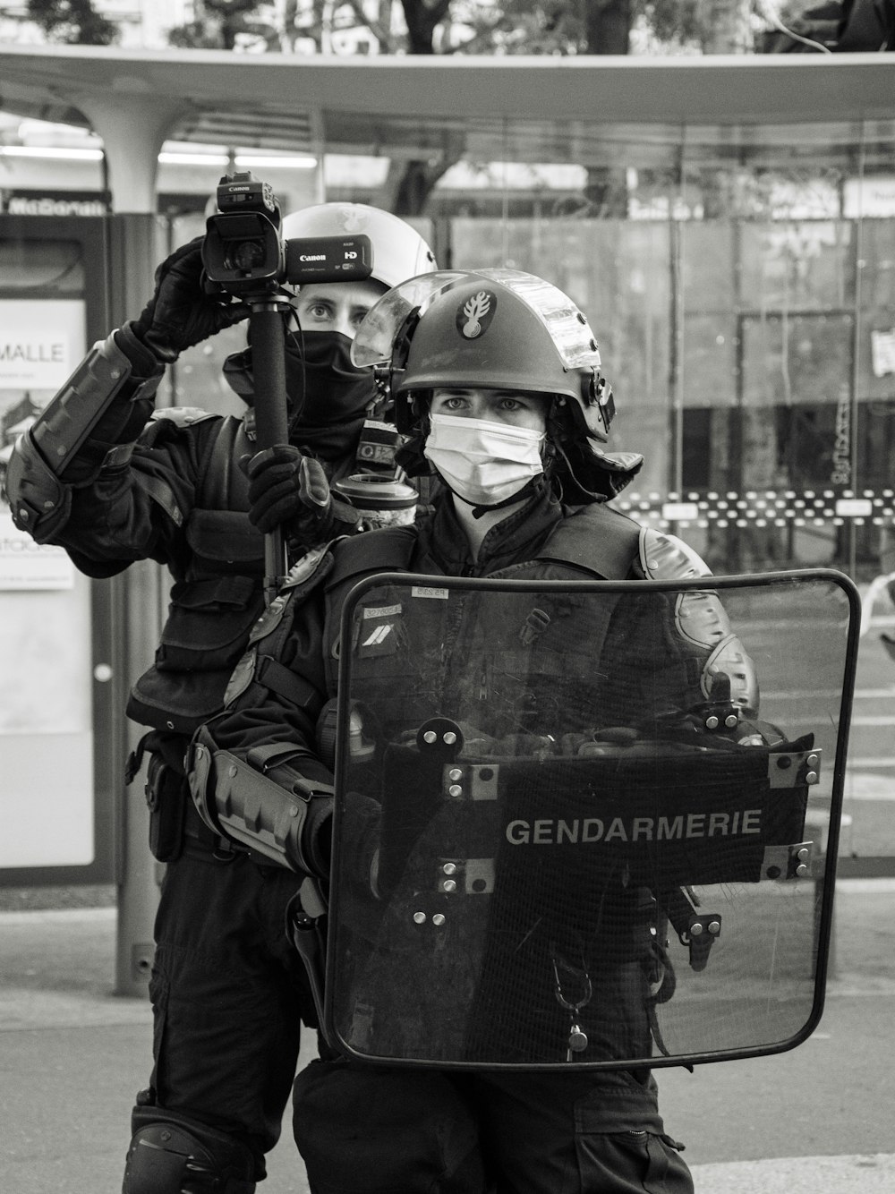 man in black and green camouflage jacket holding black dslr camera