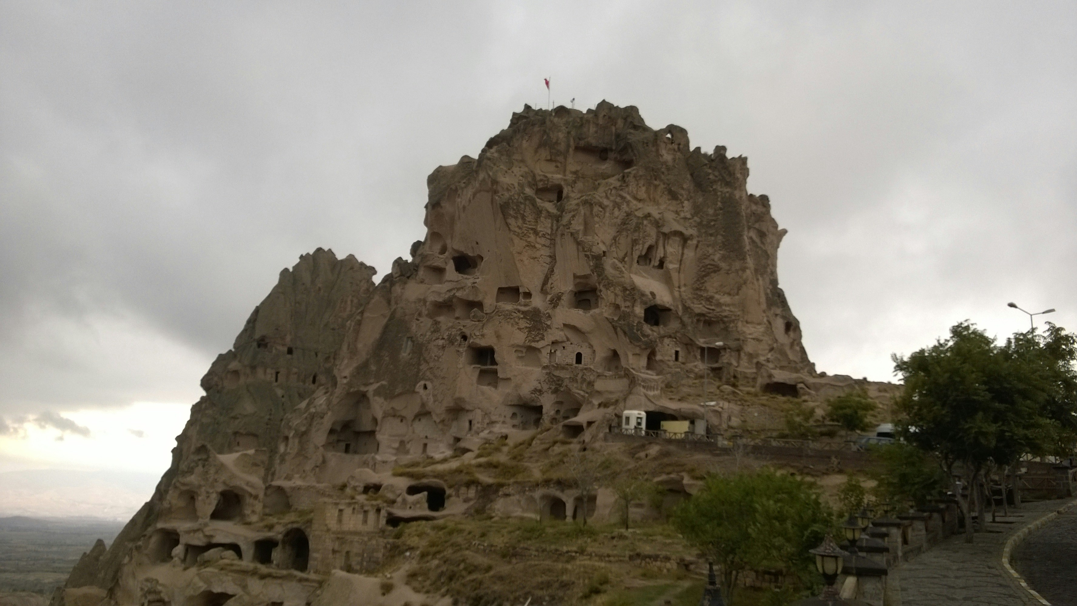 Ancient Ethiopian rock-hewn church carved into dark cliffside, dramatic highland landscape, moody overcast