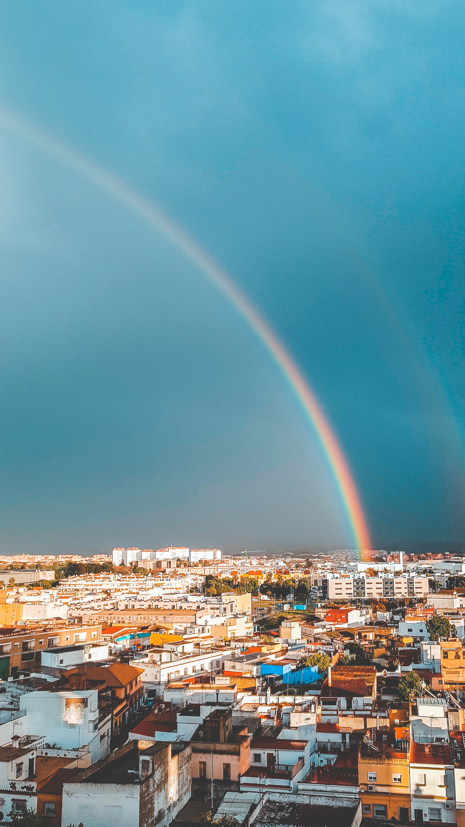 city with high rise buildings under blue sky with rainbow during daytime