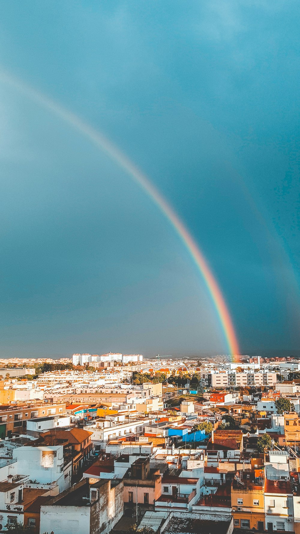 Stadt mit Hochhäusern unter blauem Himmel mit Regenbogen tagsüber