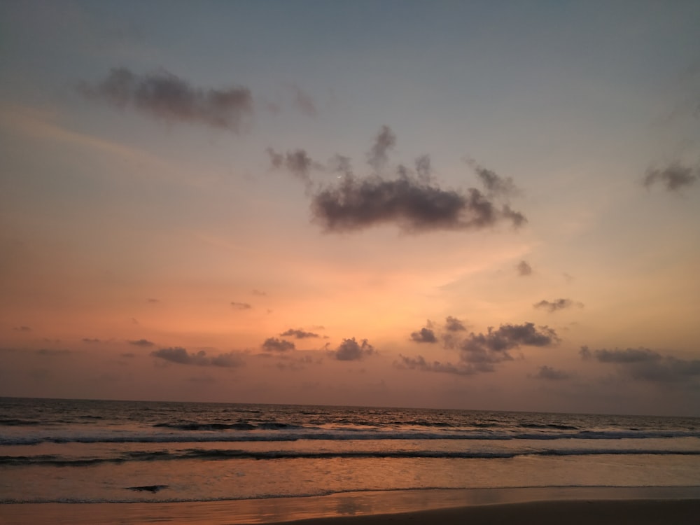 sea waves crashing on shore during sunset