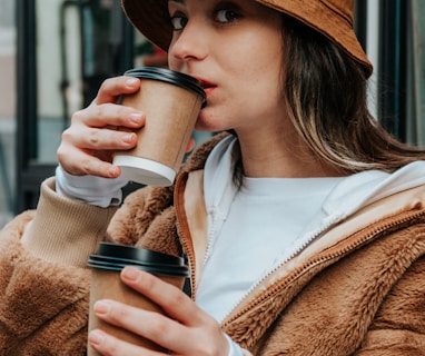 woman in brown coat holding white ceramic mug