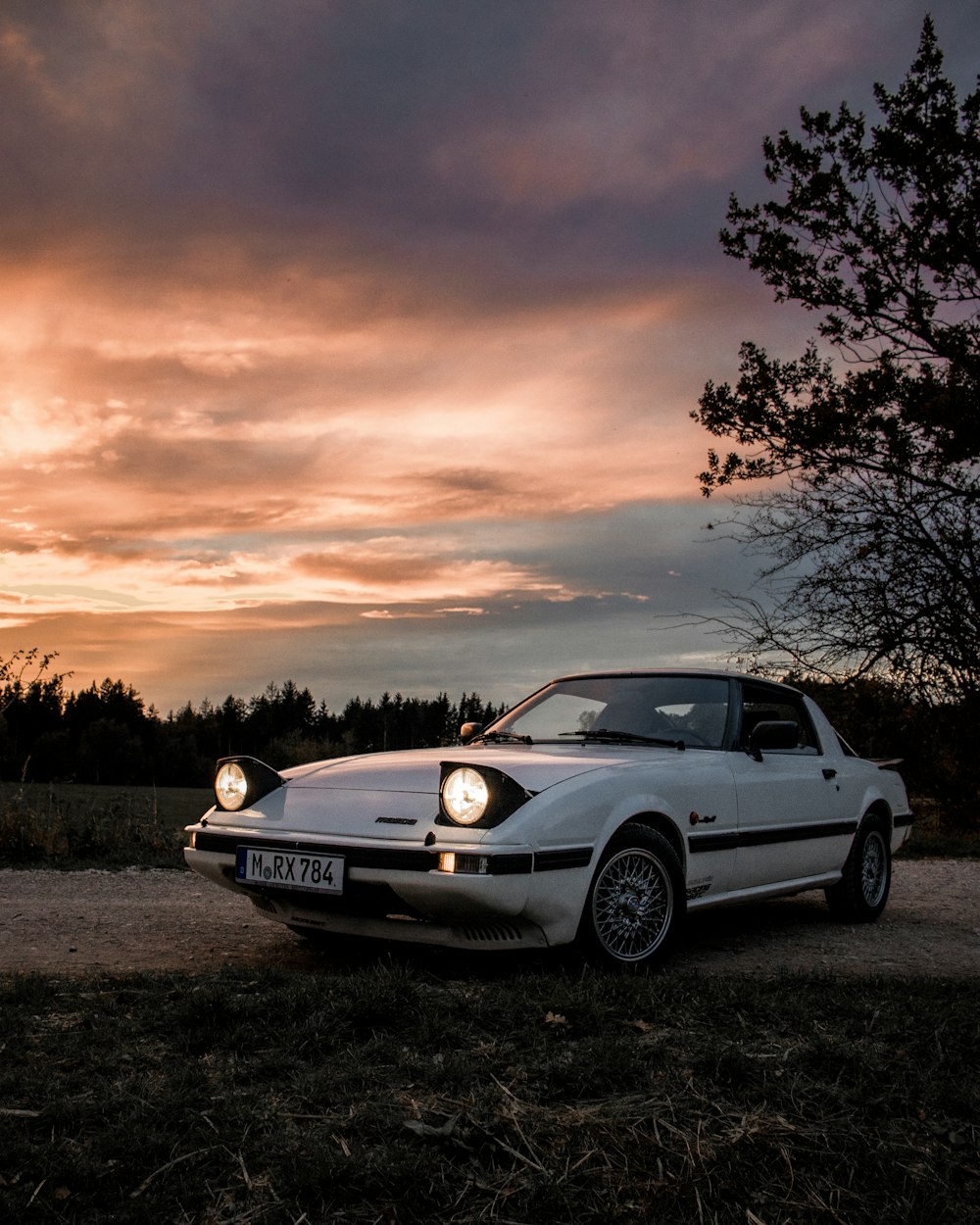 Porsche 911 blanche sur un terrain brun au coucher du soleil