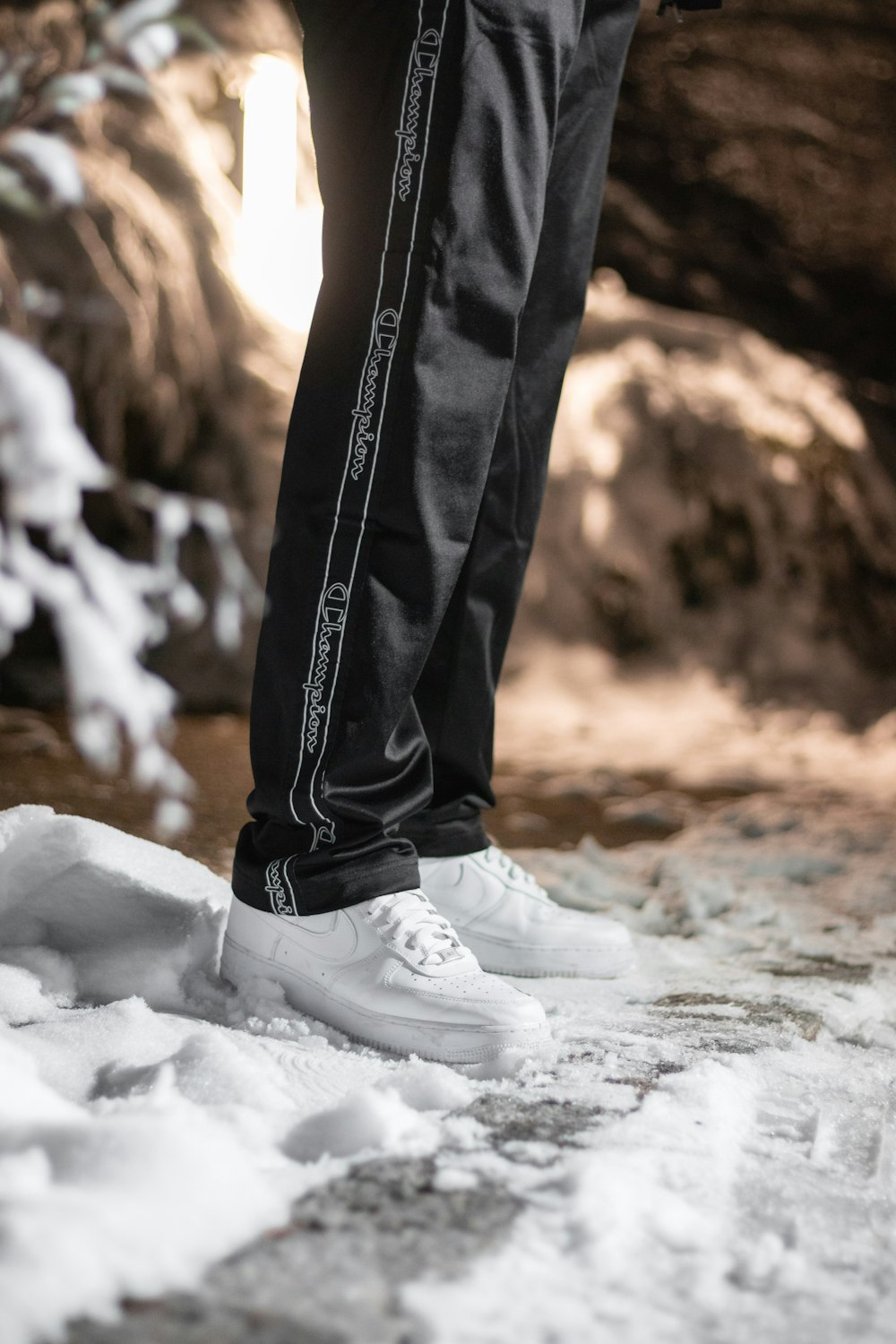 person in black denim jeans and white sneakers standing on snow covered ground during daytime