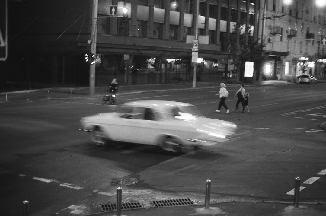 grayscale photo of man walking on sidewalk