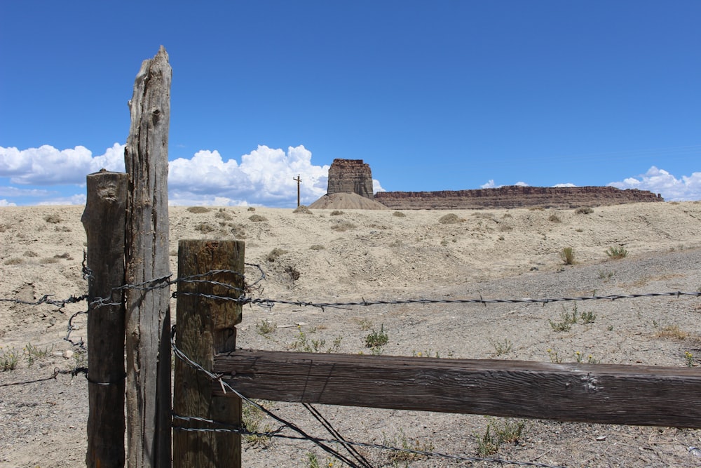 brown wooden fence near brown rock formation under blue sky during daytime