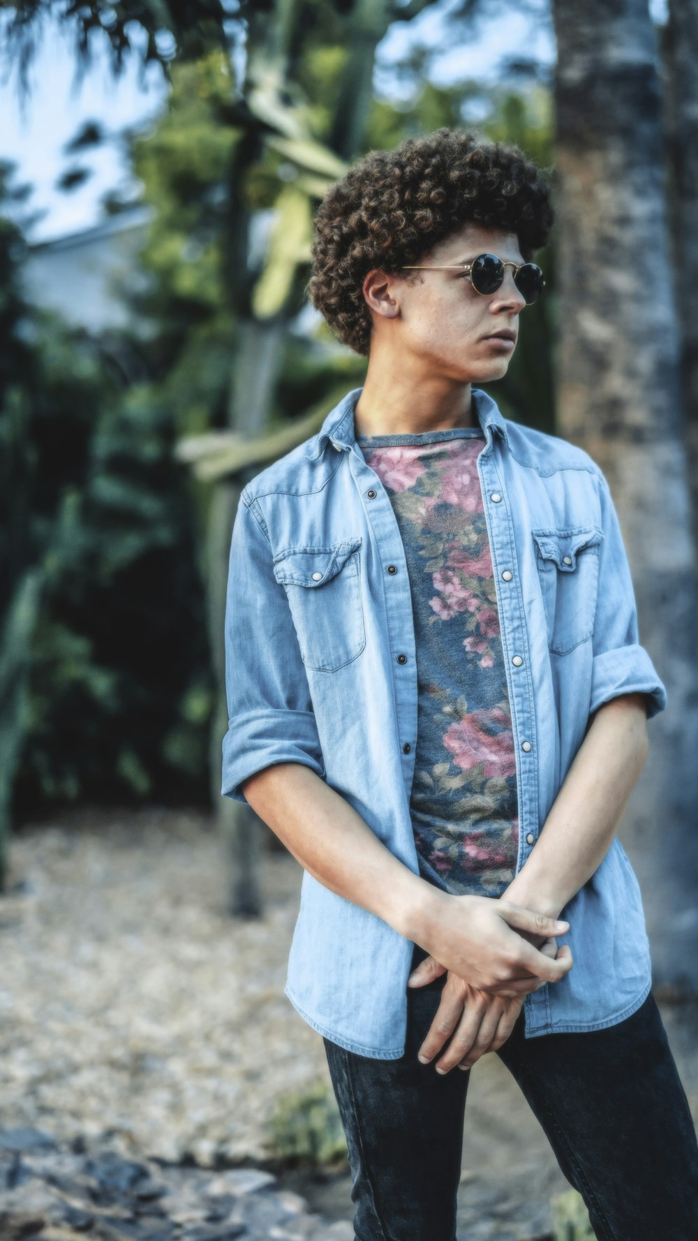 woman in blue button up shirt standing near green trees during daytime