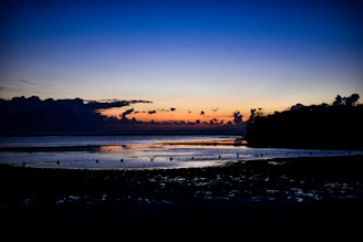 A cinematic frame of a quiet moment by the ocean at twilight, with deep shadows and rich colors
