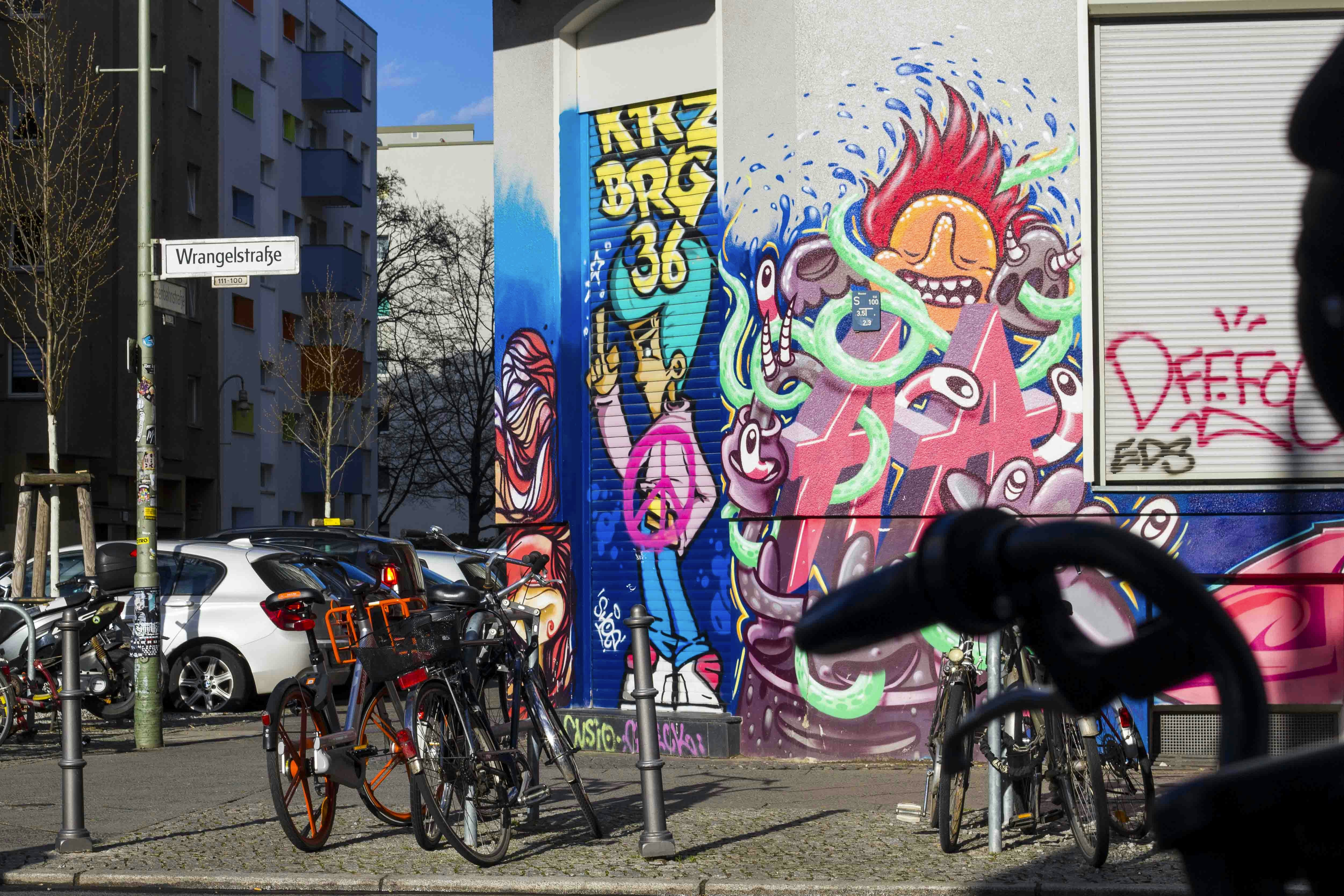 man riding bicycle near wall with graffiti