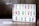 A lightbox with colorful letters displays the motivational message: 'Be Strong and Never Give Up'. The letters are in vibrant colors including green, magenta, and yellow, arranged across three lines. The background is softly blurred, giving a cozy and warm appearance.