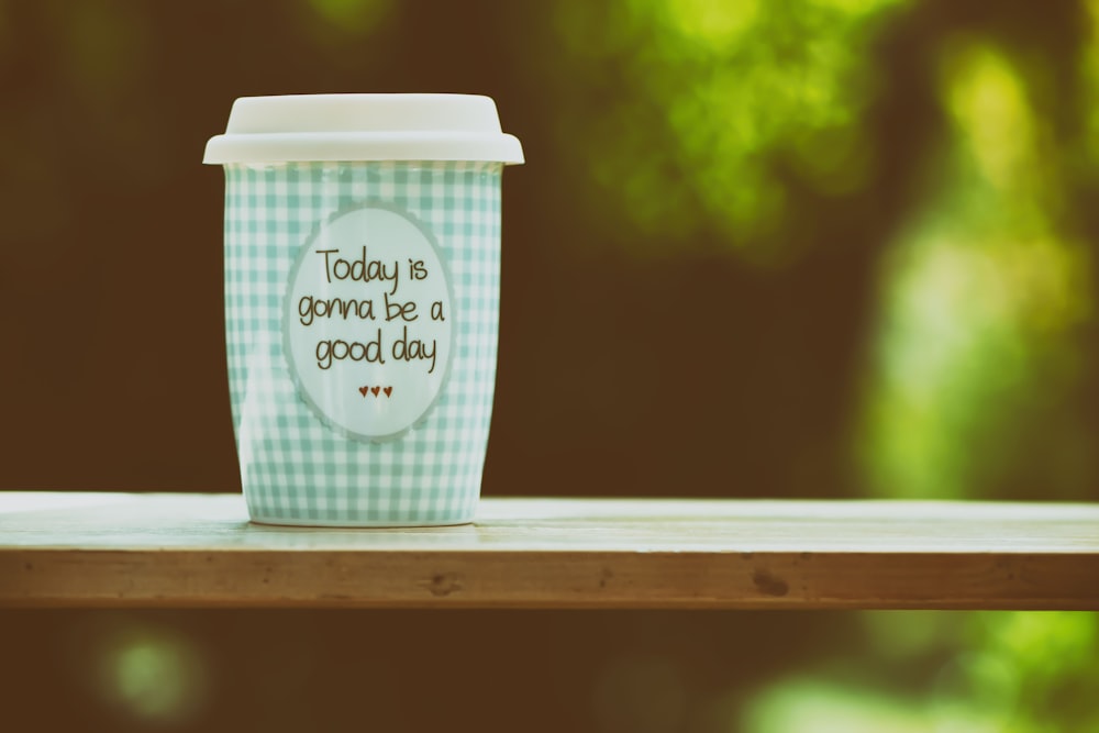 white and blue ceramic mug on brown wooden table