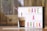 A glass of iced coffee with a frothy top and a pink straw is placed next to a lightbox with the words 'HAVE A BREAK' in colorful letters. The background features a blurred indoor setting with warm lighting.