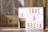 A glass of iced coffee with a frothy top and a pink straw is placed next to a lightbox with the words 'HAVE A BREAK' in colorful letters. The background features a blurred indoor setting with warm lighting.