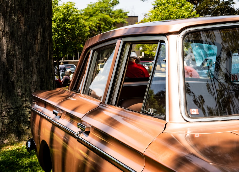 brown and black car parked near green trees during daytime