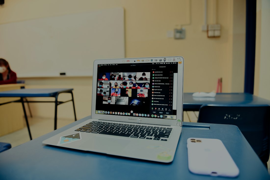 Laptop showing an online class video call in an empty classroom