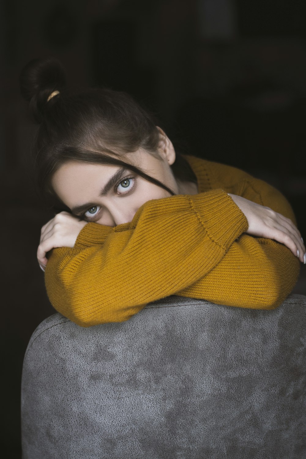 woman in yellow knit sweater covering her face with yellow scarf